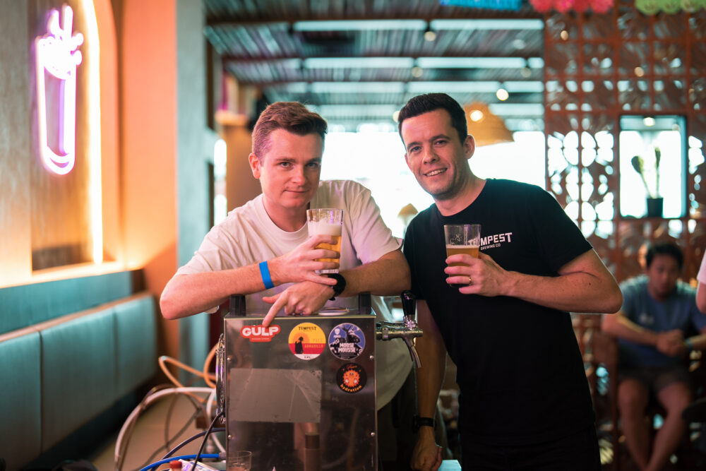 Two men standing over a beer serving machine